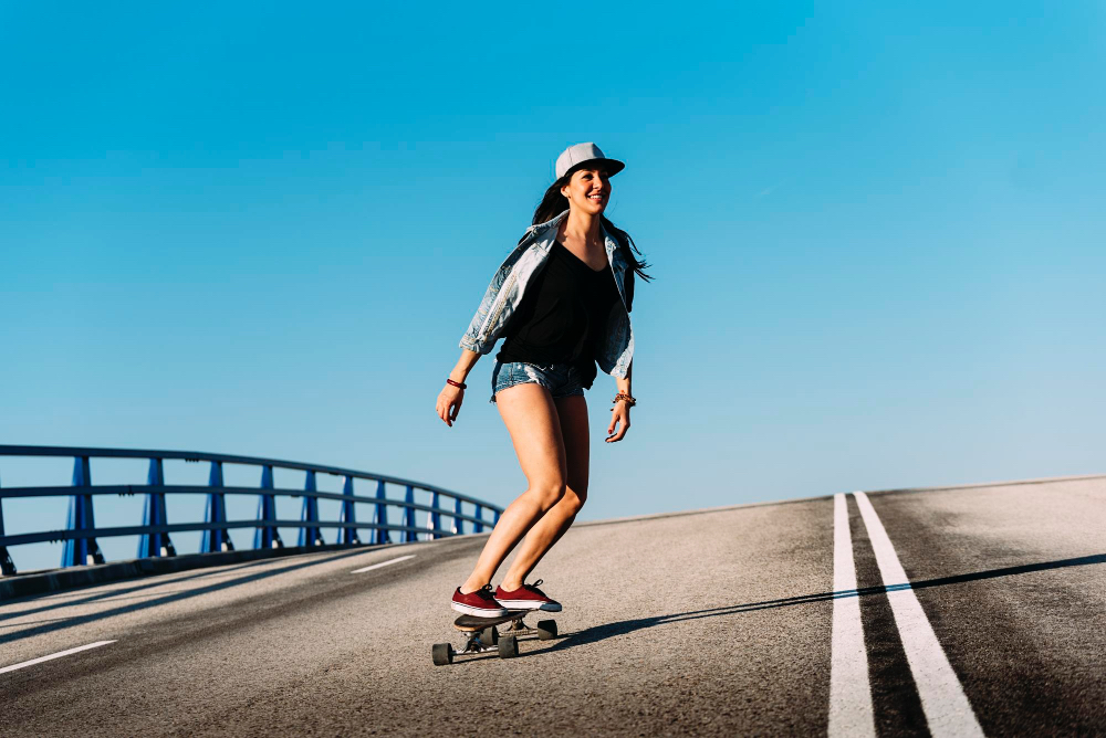 Junge Frau fährt Longboard auf einer breiten Strandpromenade in Südwestfrankreich