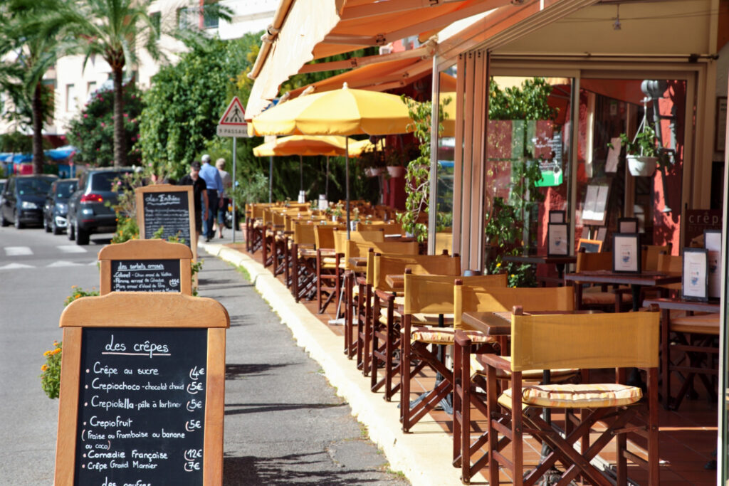 Typisches französisches Straßencafé mit Tischen und Menütafel vor dem Restaurant