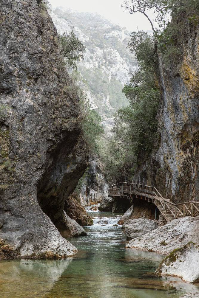 Wanderweg durch eine enge Schlucht in den Pyrenäen mit Holzsteg und klarem Bergfluss