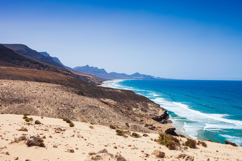 Blick auf die wilde Küstenlandschaft von Fuerteventura mit Bergen und Atlantik – perfekter Ort zum Surfen