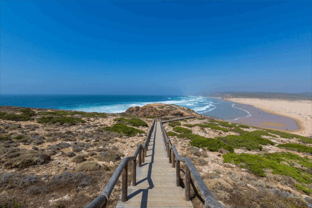Holzsteg führt über die Dünen zum Strand an der Algarve mit Blick auf den Atlantik