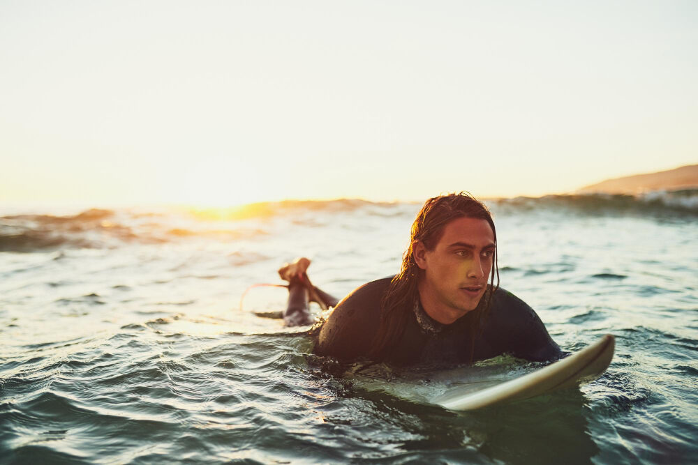 Surfer im Wasser beim Sonnenuntergang an der spanischen Atlantikküste