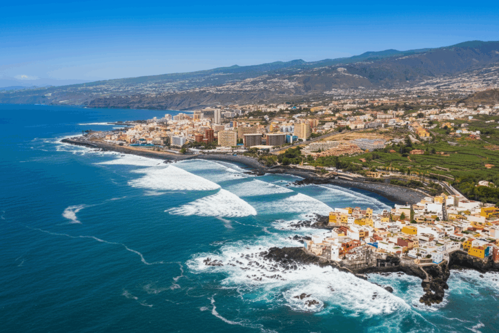 Luftaufnahme von Puerto de la Cruz an der Nordküste Teneriffas mit rauer Brandung und schwarzen Lavastränden – ein Hotspot für Surfen und Küstenabenteuer.