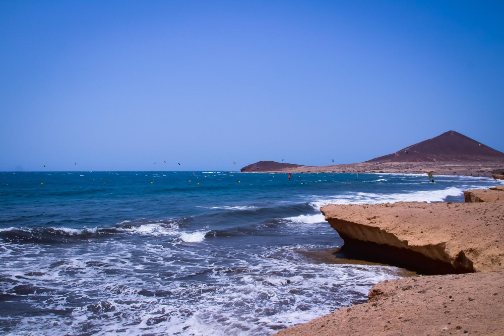 Kitesurfer am Strand von El Médano mit Blick auf die Montaña Roja – beliebter Spot an der Südküste Teneriffas zum Surfen und Kitesurfen.