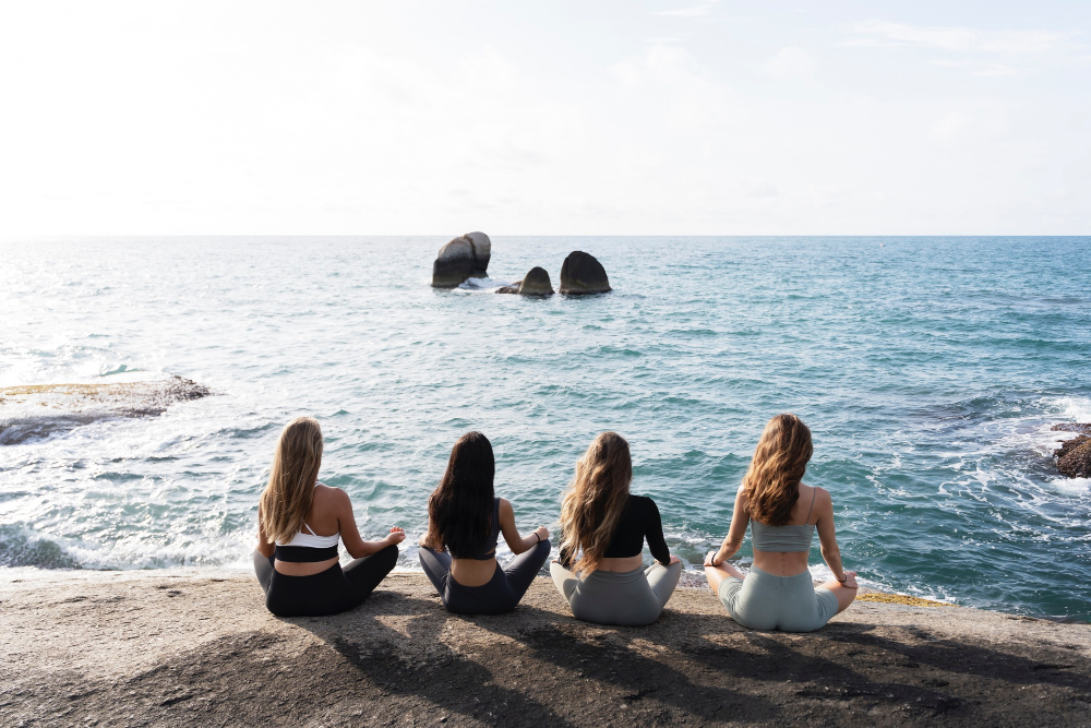 Vier Frauen beim Yoga am Meer auf Teneriffa – Ruhe, Achtsamkeit und Entschleunigung mit Blick auf den Atlantik.
