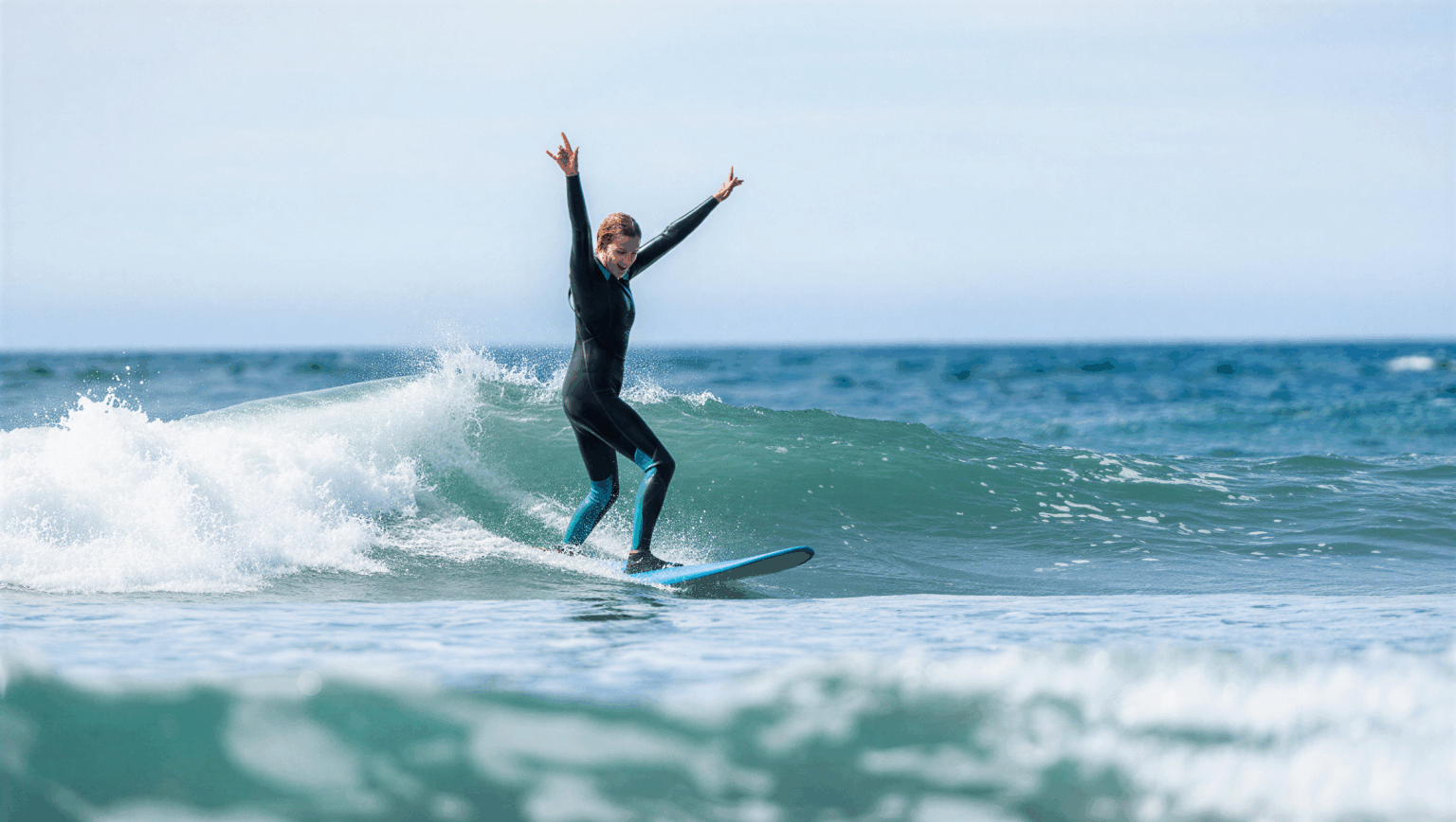 Surferin jubelt auf ihrer ersten Welle während eines Surfkurses im Surfcamp – Freude und Erfolgsmoment auf dem Meer.